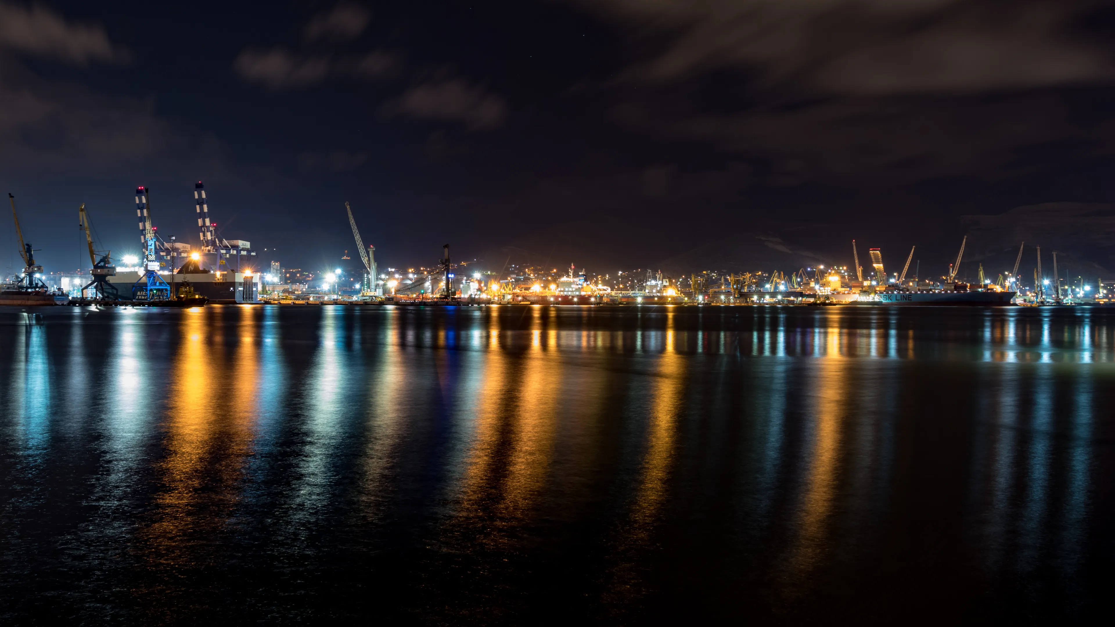 Explore the beauty of a harbor illuminated at night, showcasing vibrant reflections on the calm water.