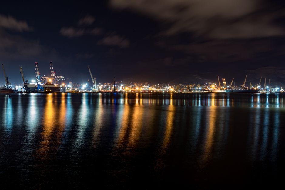 Explore the beauty of a harbor illuminated at night, showcasing vibrant reflections on the calm water.