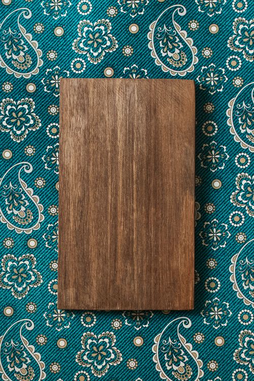 Free A wooden board on vibrant Islamic patterned fabric, top view composition. Stock Photo