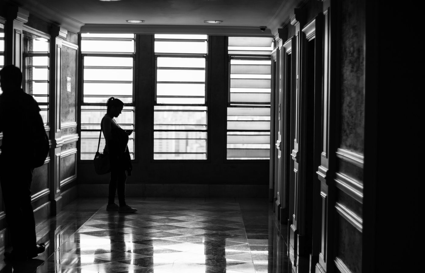 Silhouettes in a modern hallway with geometric window patterns.