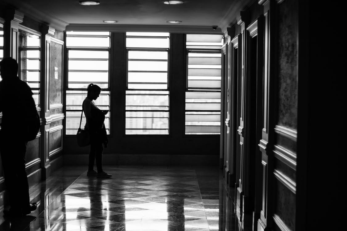Free Silhouette Photography of Person Standing Near Window Stock Photo