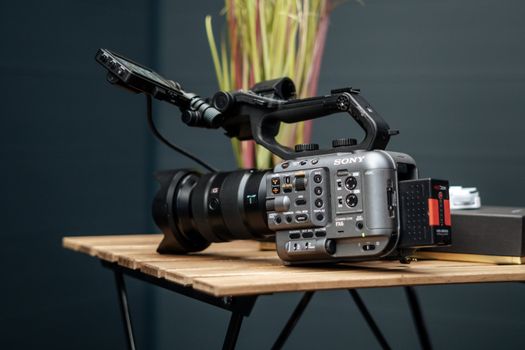 Close-up of a professional video camera setup on a wooden table, indoors.