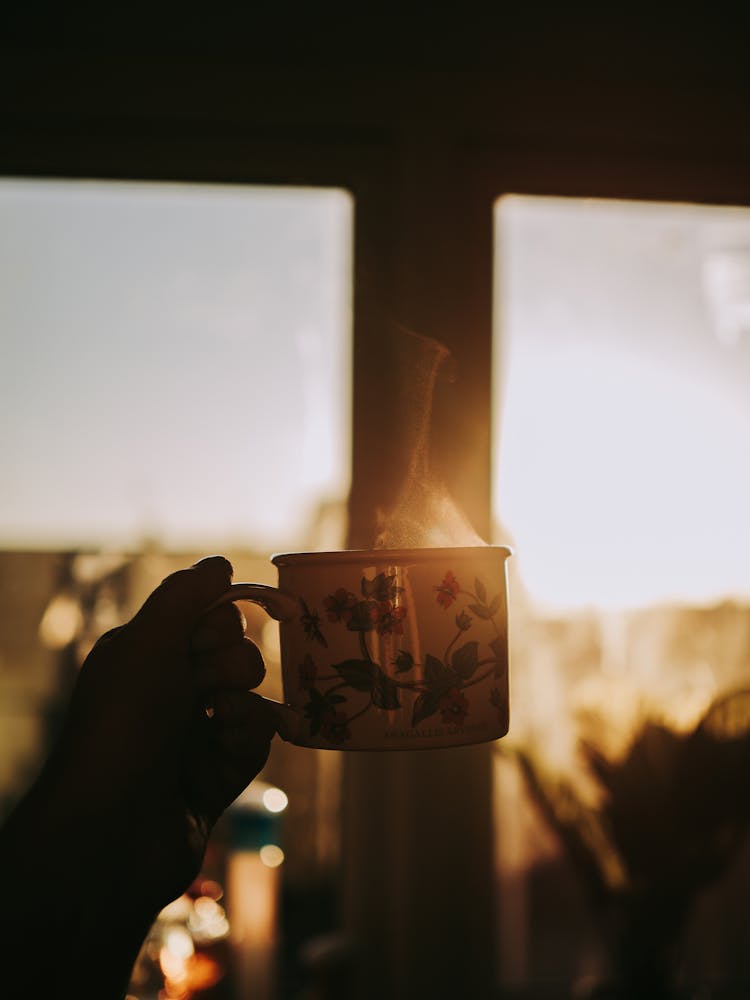 Person Holding Steaming Mug Of Coffee