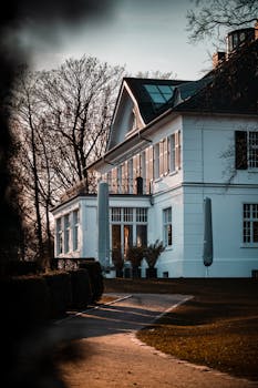 Charming white house with classic architecture and serene garden pathway in Hamburg, Germany at sunset.