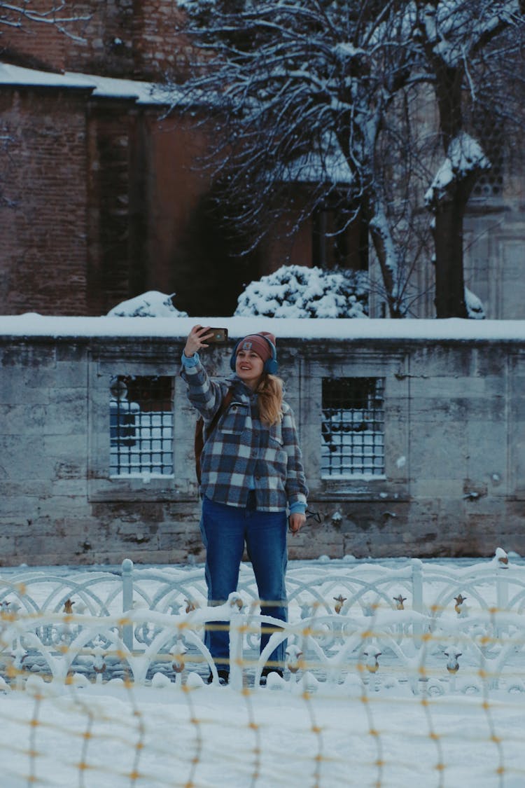 Girl Standing In Snow And Taking A Selfie