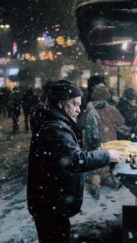 A street vendor serves food on a snowy night in bustling Istanbul, Turkey.
