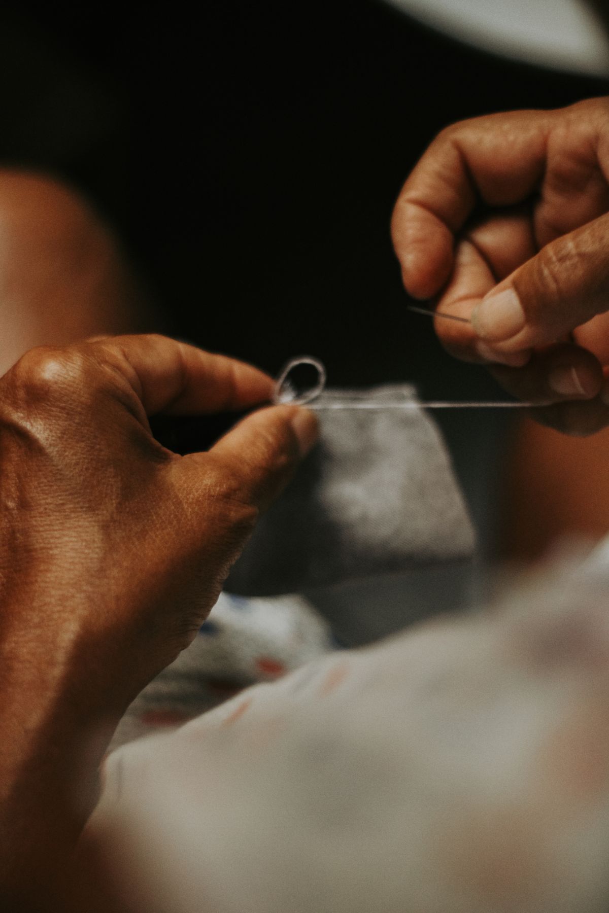 Hands doing precise sewing work with a needle and thread