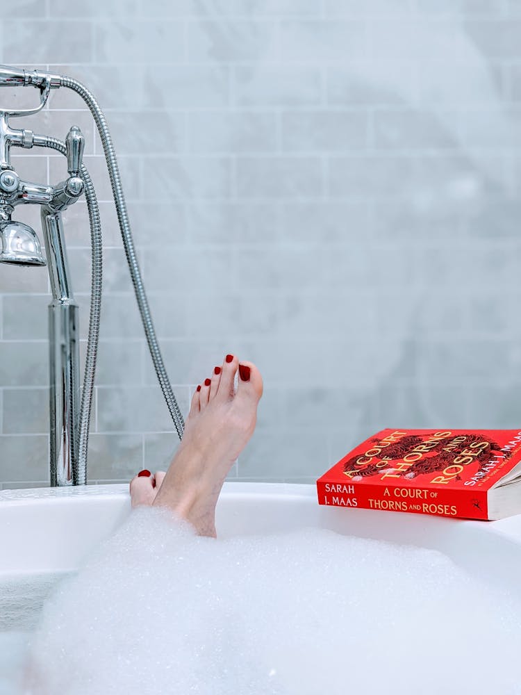 Bare Feet And A Book On The Bathtub