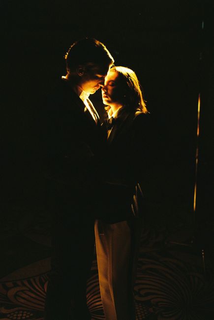 A couple in an intimate embrace, illuminated against a dark background, exuding romance.