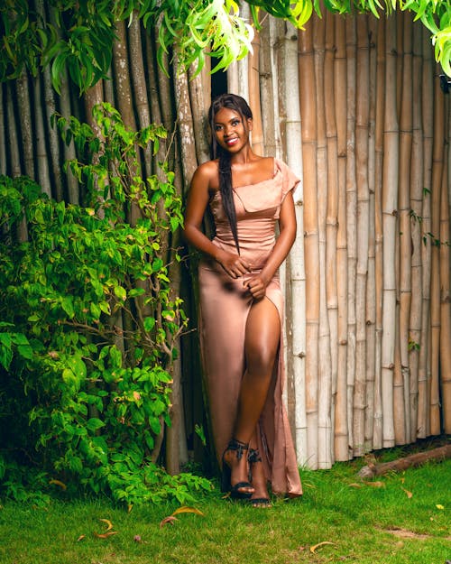 Woman in a Beige Dress Standing Near Green Leaves