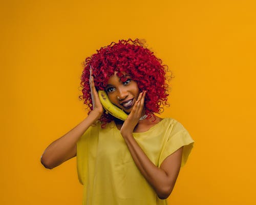 Photo of a Woman with Red Curly Hair Holding a Yellow Banana