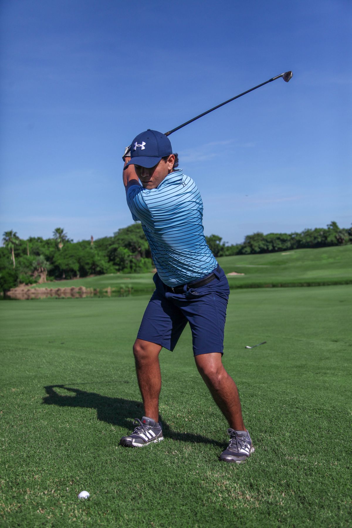 Golfer swinging through impact and into the follow through