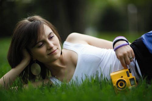 Free Woman in a White Tank Top Lying on the Grass Stock Photo