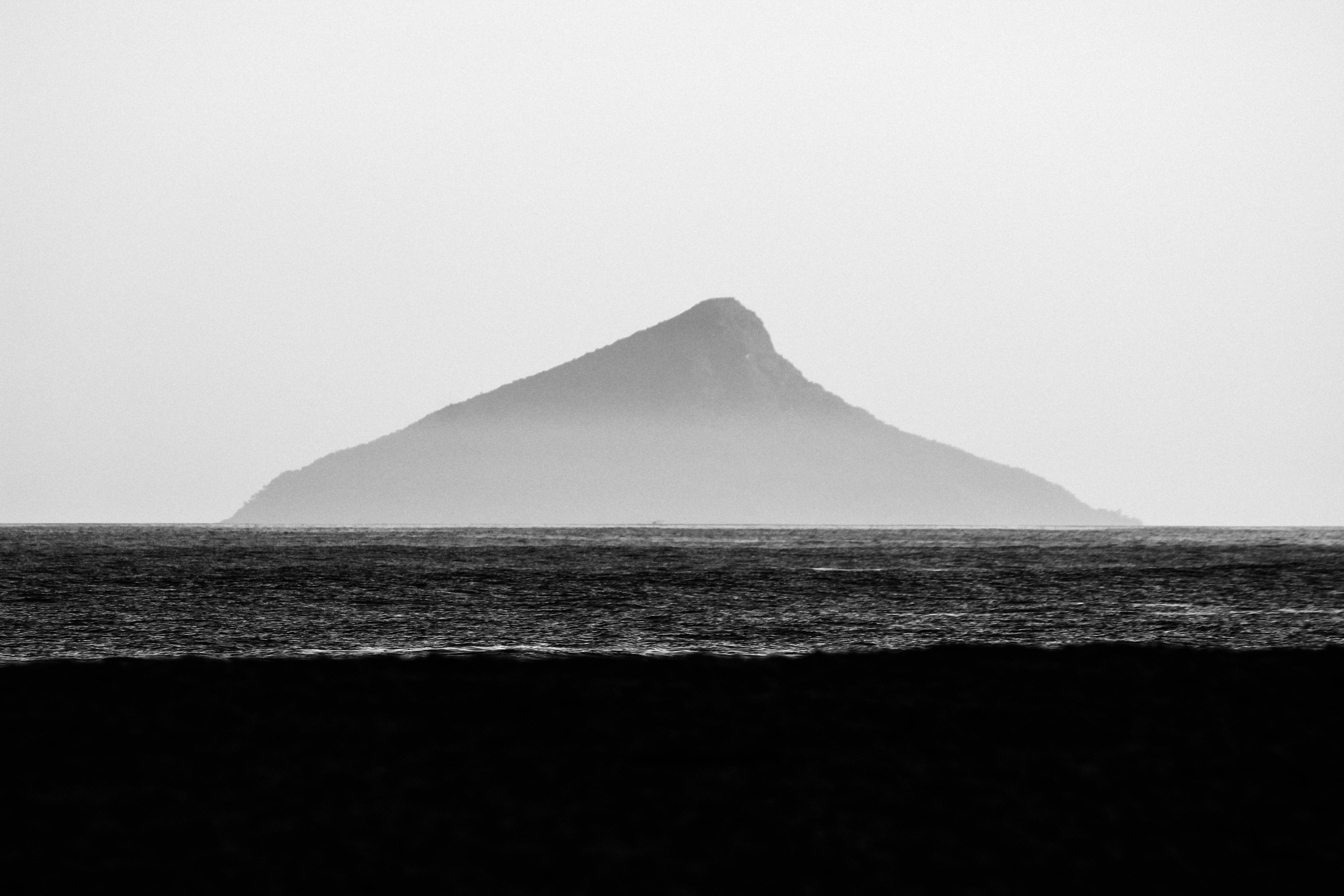 A black and white shot of a serene ocean view with a distant island off Brazil's coast.