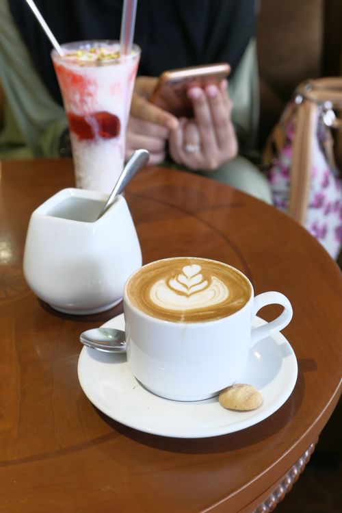 Free A latte with latte art and dessert in a cozy café setting, perfect for coffee lovers. Stock Photo