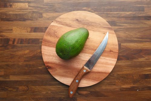 Free Top view of avocado on a wooden chopping board with a knife, perfect for culinary and healthy eating themes. Stock Photo