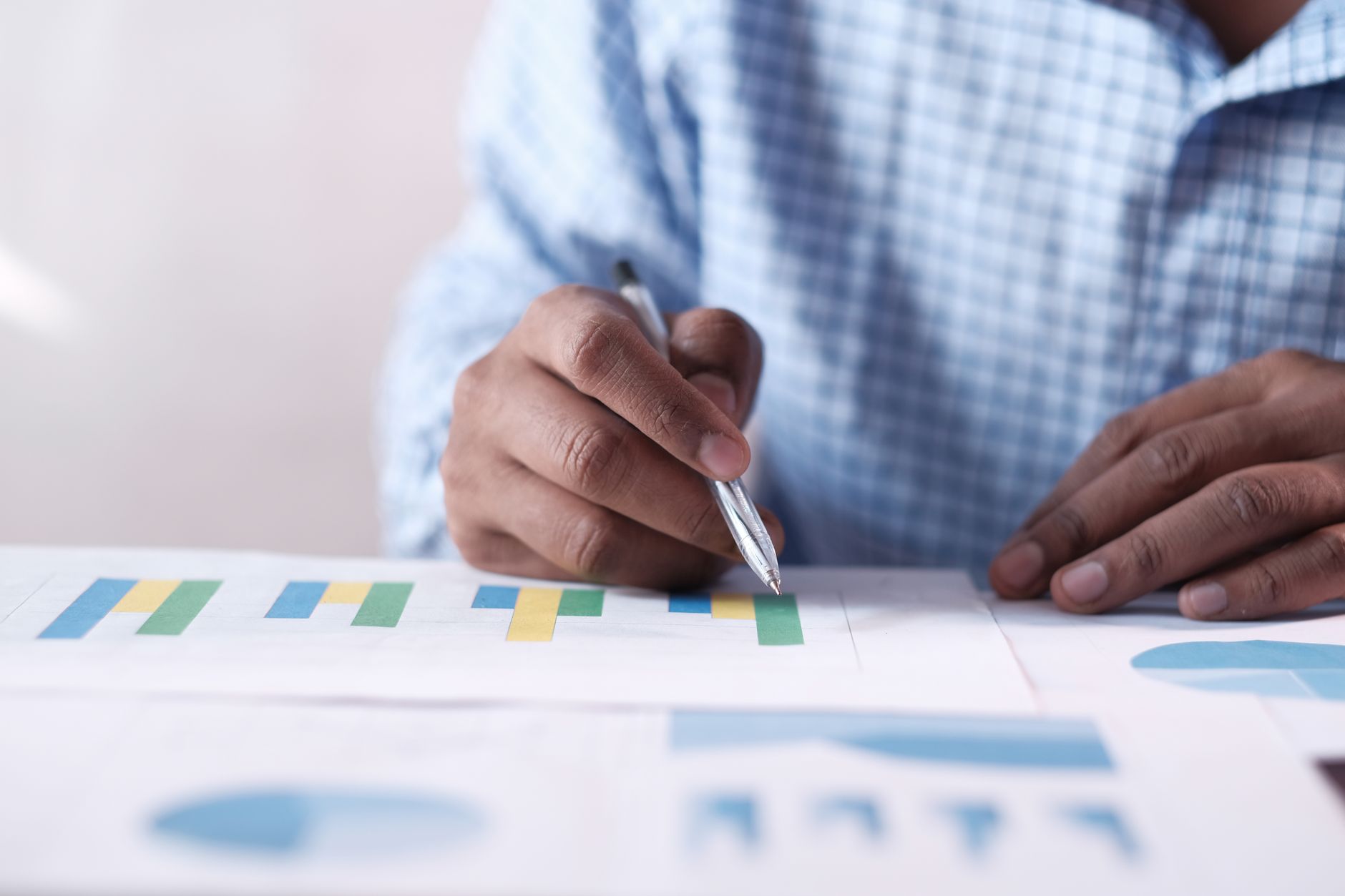 Close-up of hands analyzing colorful graphs, indicating business planning.