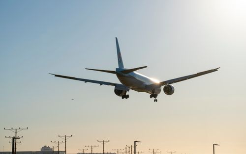 Free Commercial airplane landing at sunset at Los Angeles Airport, showcasing aviation against a clear sky. Stock Photo