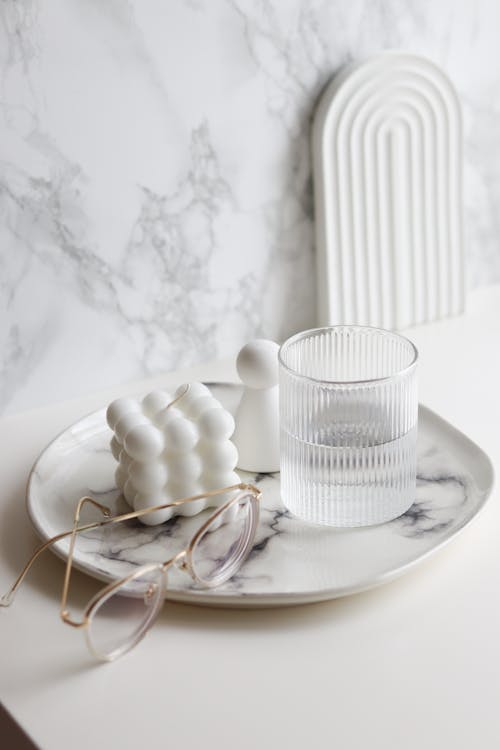 Specs Lying on Plate Next to Candle and Glass of Water