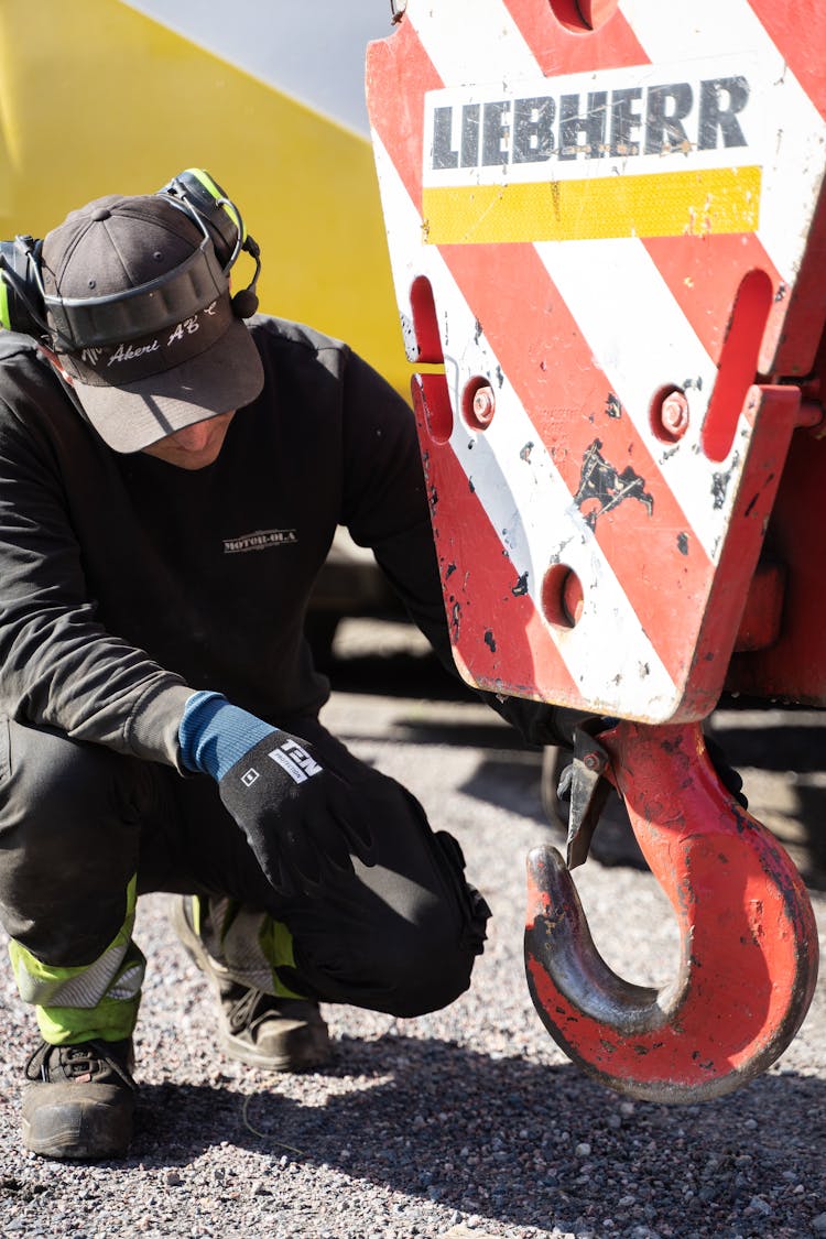 Worker Crouching Near Hook