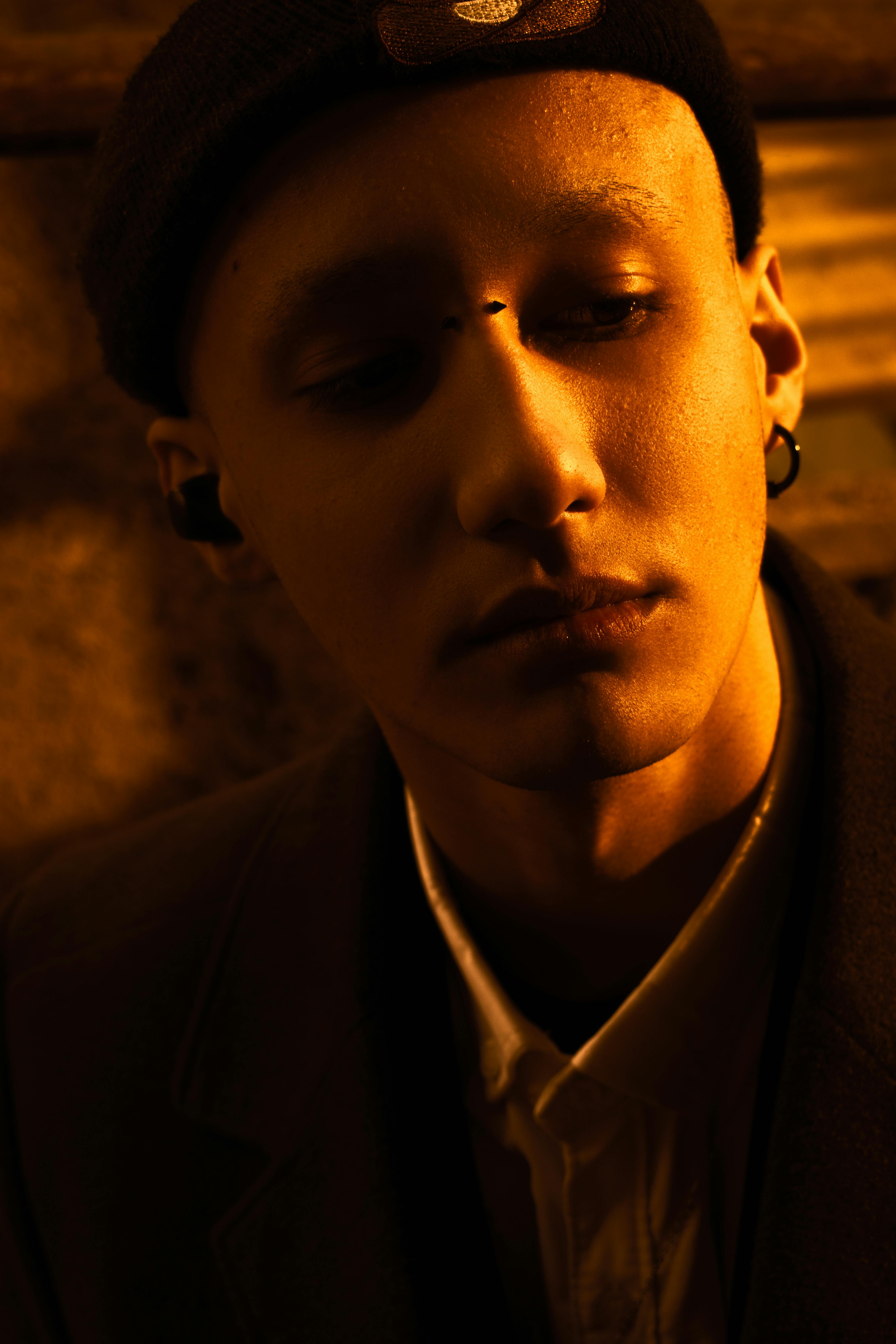 Dramatic portrait of a young man with warm lighting, highlighting thoughtful expression.