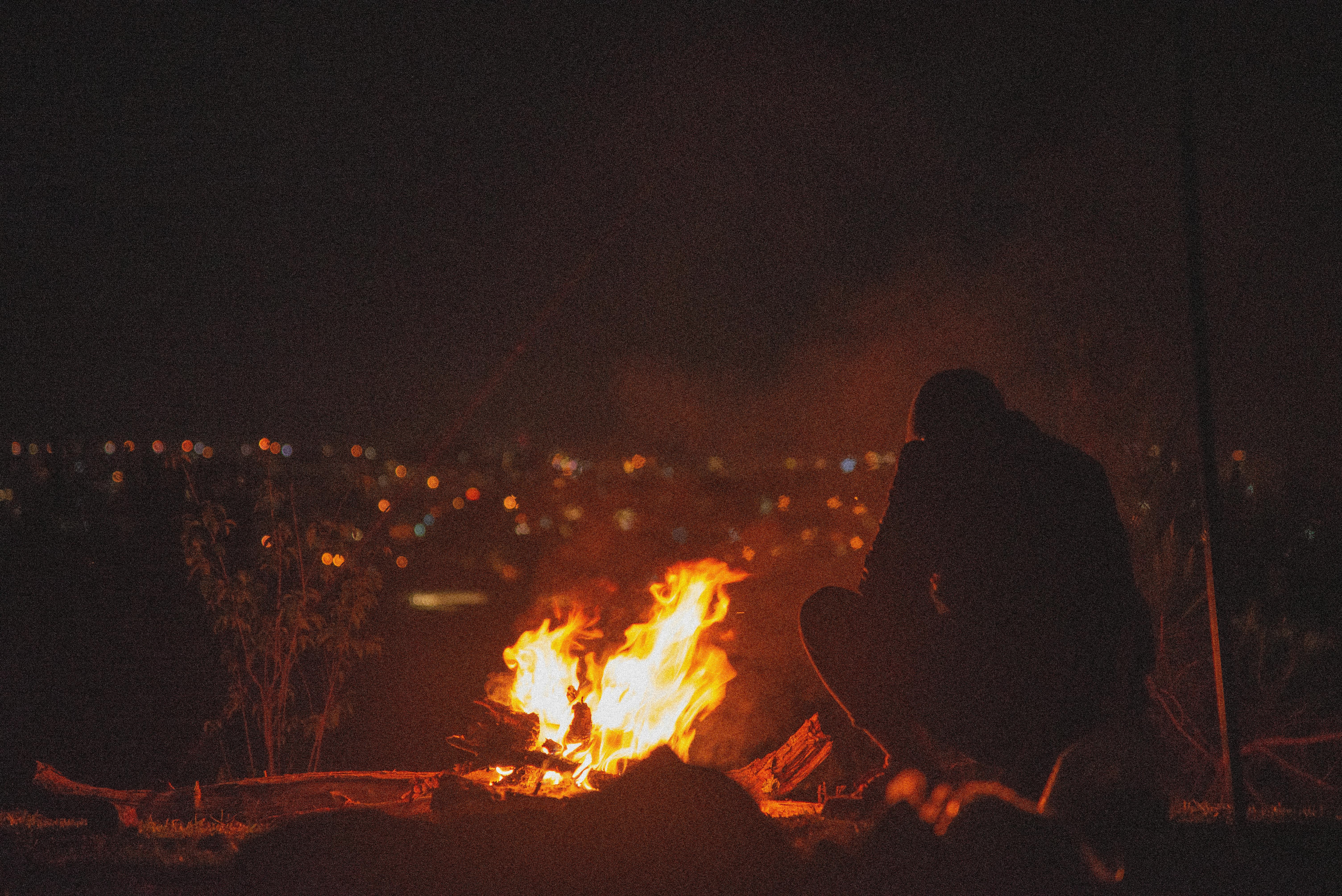 a man sitting near bonfire during night