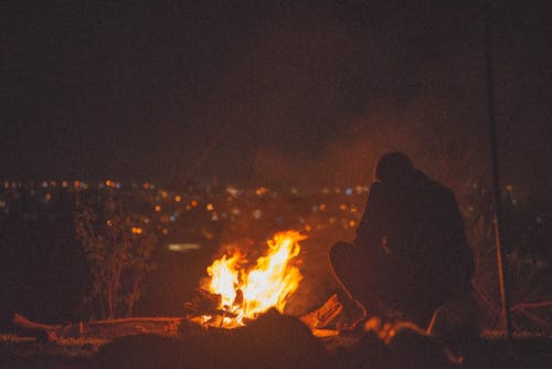 A Man Sitting Near Bonfire during Night 