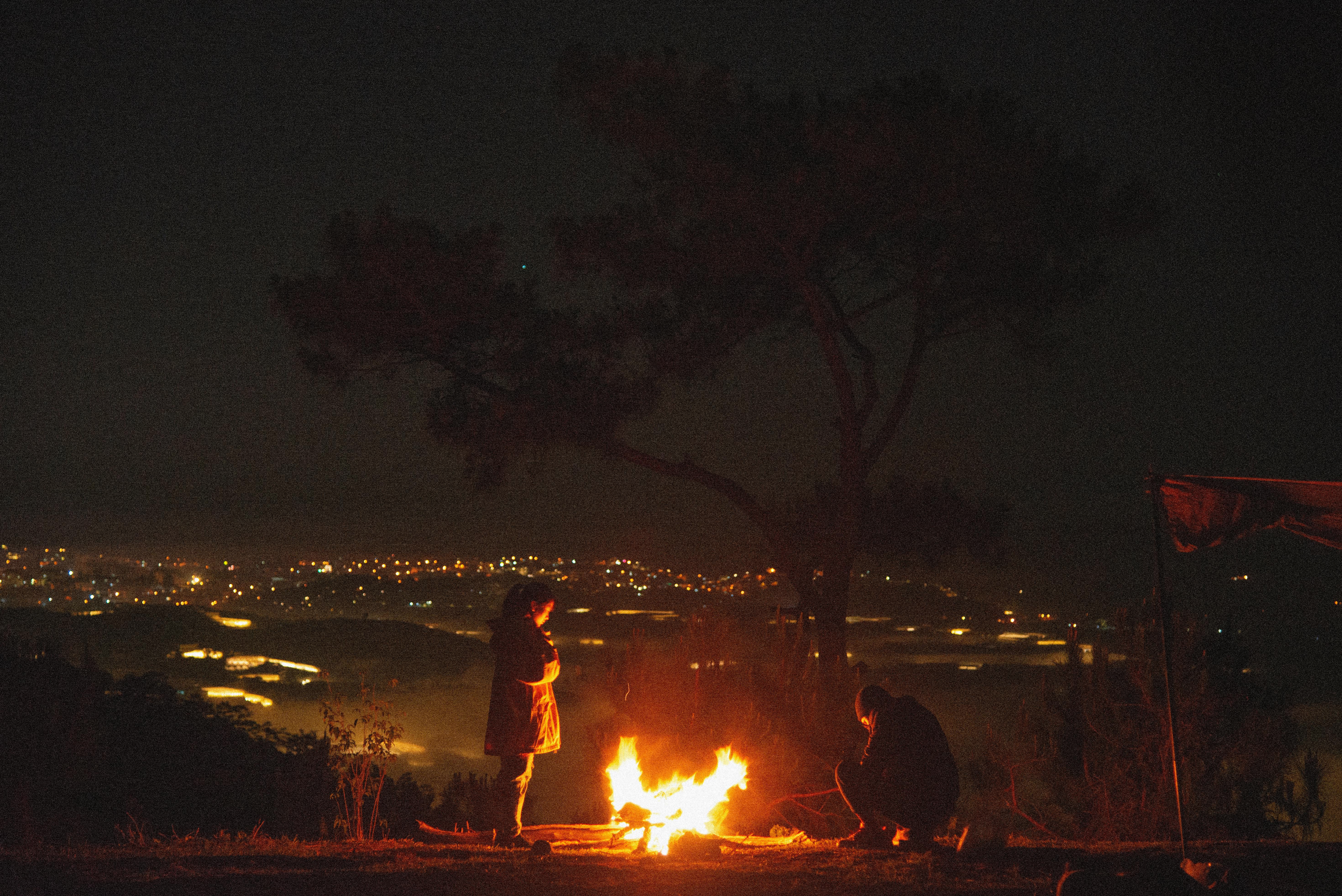 a woman standing near bonfire during night time