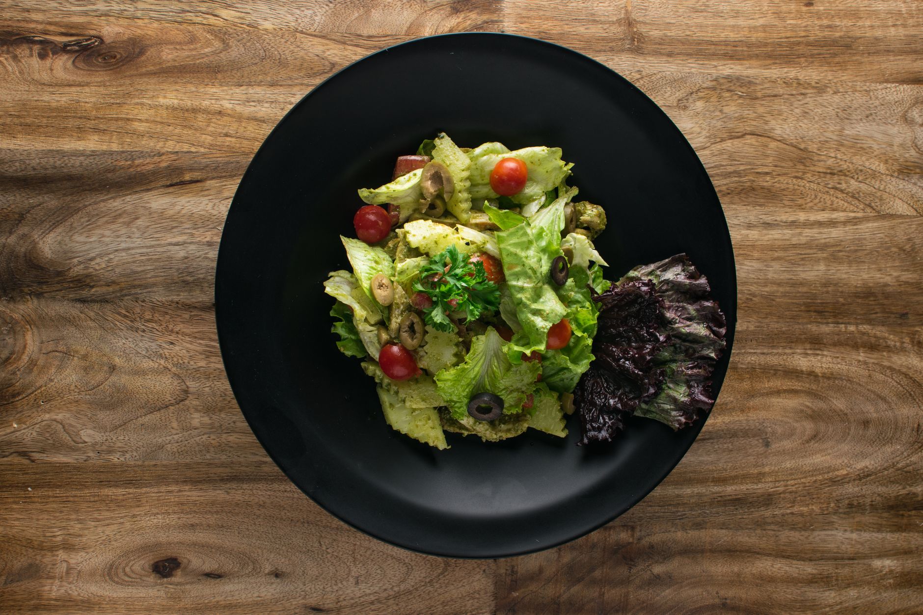 A glass of sparkling water next to a colorful fresh Italian deli salad