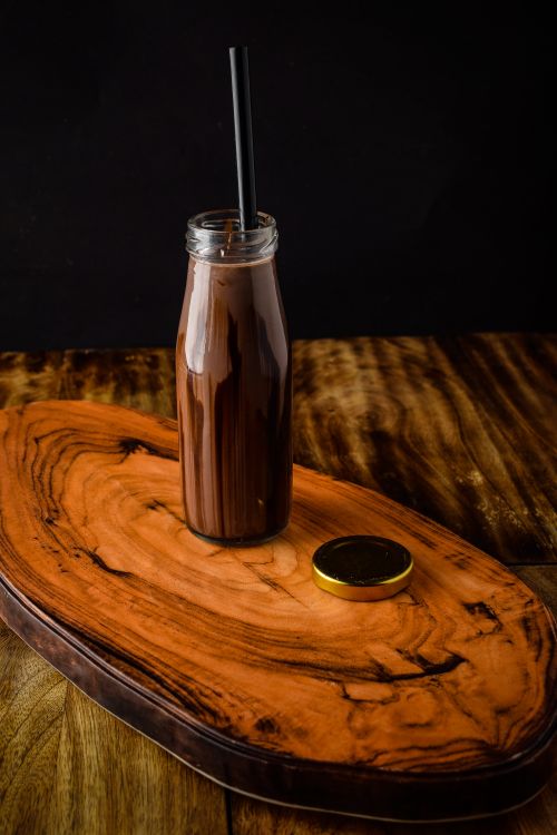Free Delicious chocolate milkshake in glass bottle on wooden board with dark background. Stock Photo