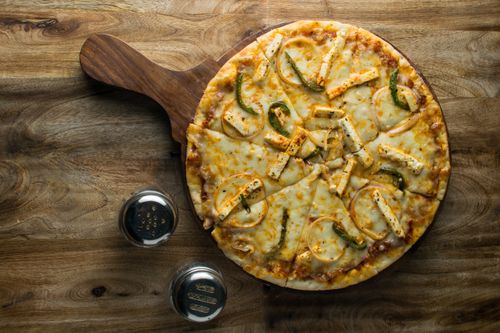 Free Delicious pizza topped with cheese and vegetables on a wooden board, perfect for food lovers. Stock Photo
