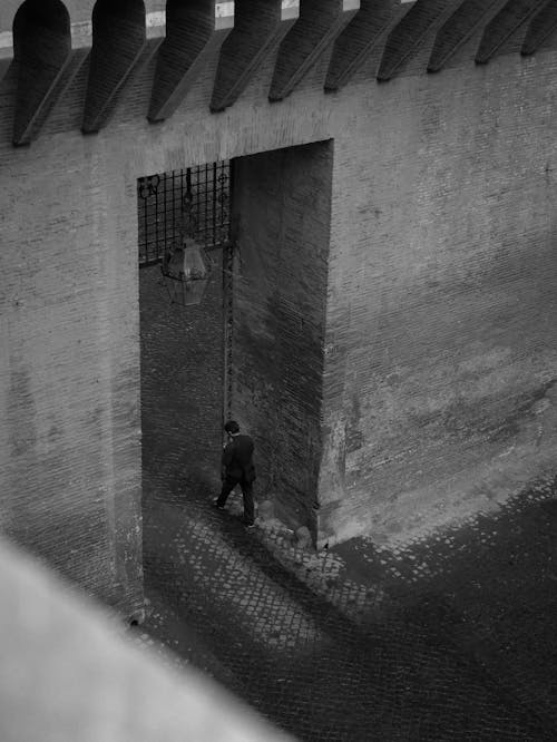 Free Grayscale Photo of a Man Walking at the Doorway Stock Photo