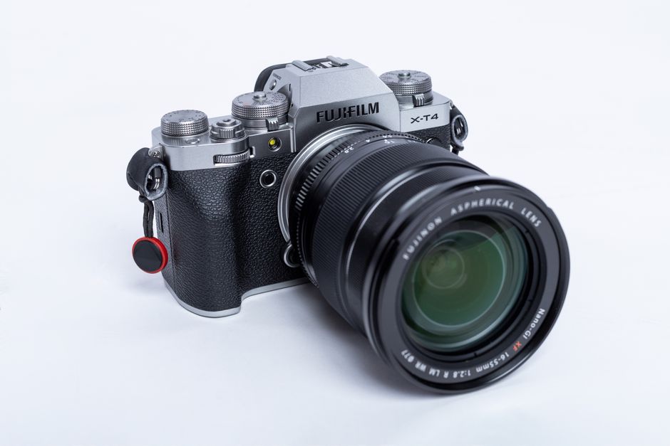 Câmera mirrorless Fujifilm X-T4 com lente telefoto em fundo neutro