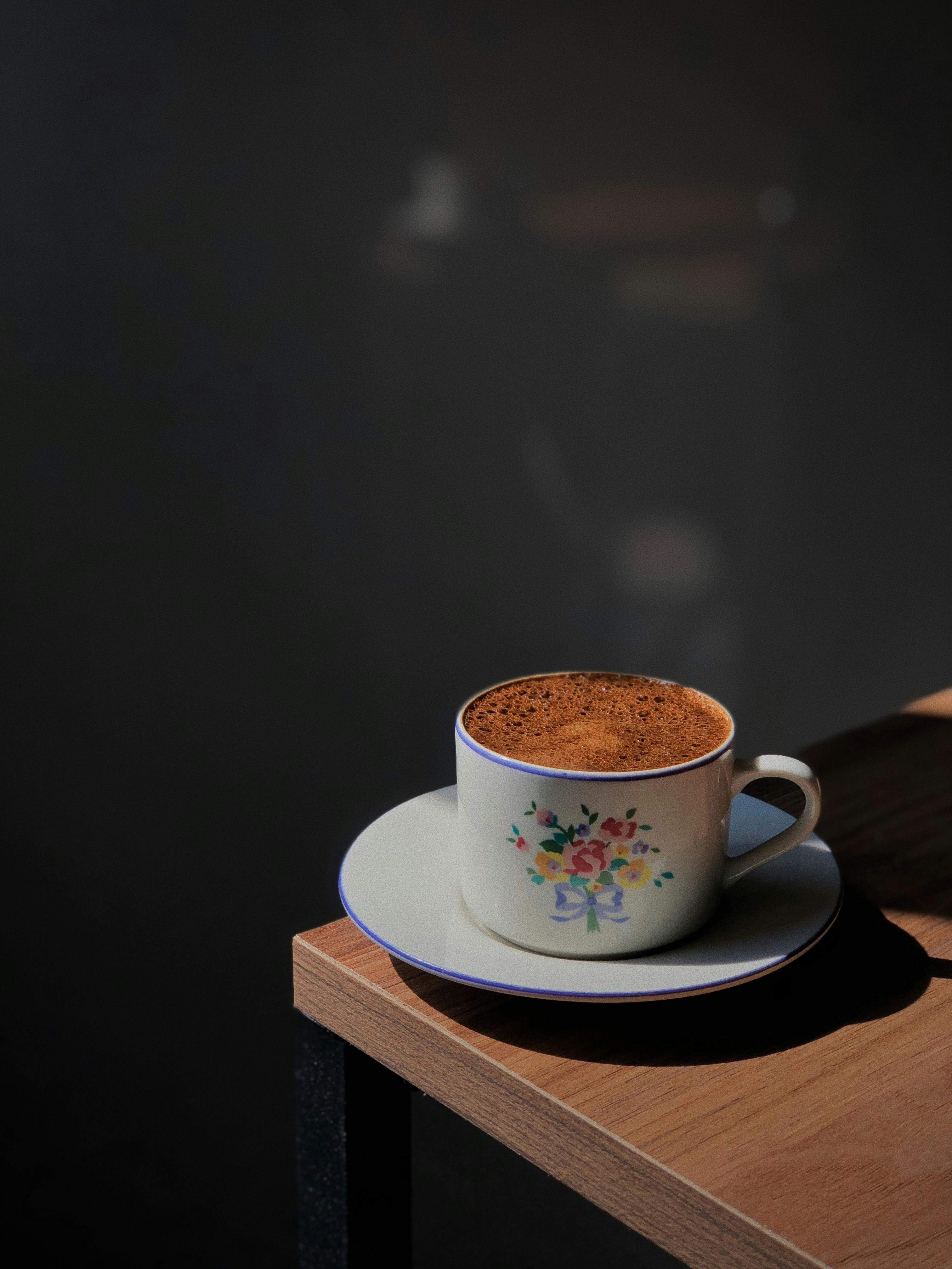 A beautifully crafted cappuccino in a floral cup on a wooden table, perfect for a cozy morning.