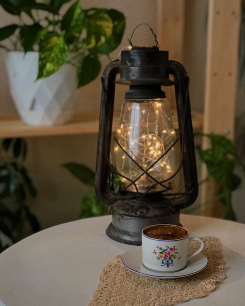 Free Warm indoor scene with a coffee cup and lantern on a table, ideal for cozy settings. Stock Photo
