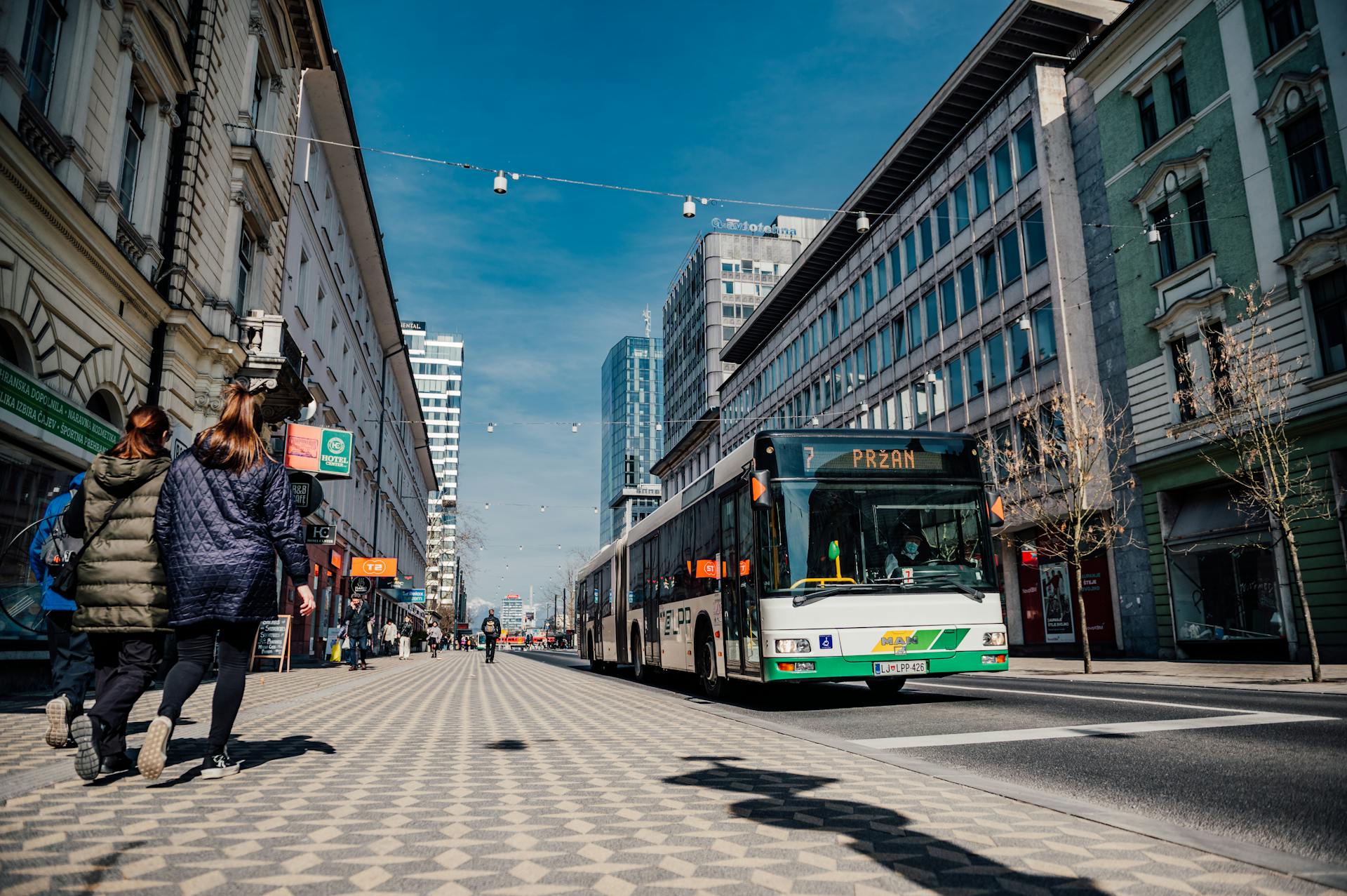 Street scene in Ljubljana featuring public transportation bus and pedestrians.
