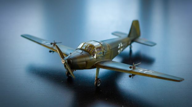 Close-up of a realistic model airplane with propeller on a dark surface, showcasing intricate details.