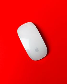 Stylish wireless mouse placed on a bold red surface, showcasing modern design.