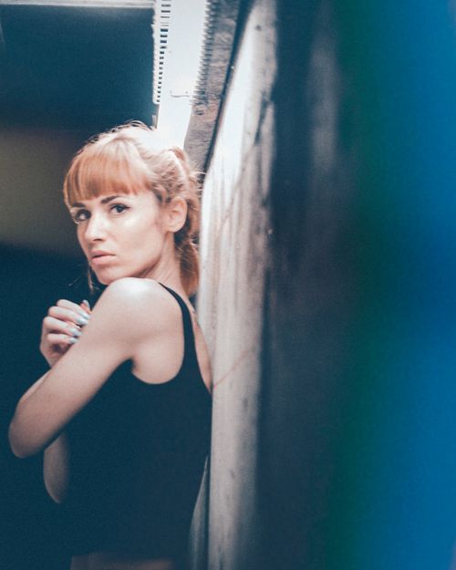 Free A thoughtful woman stands indoors, captured in soft, muted lighting with a classic portrait style. Stock Photo