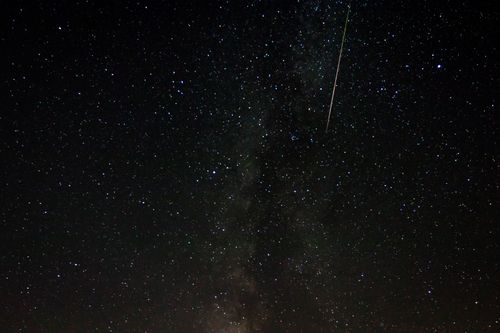 Free Capture of the Milky Way galaxy with visible meteor streak in a star-filled night sky. Stock Photo