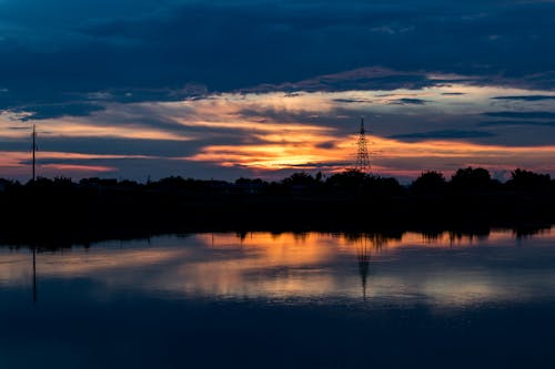 Silhouette of Trees Near Body of Water during Sunset