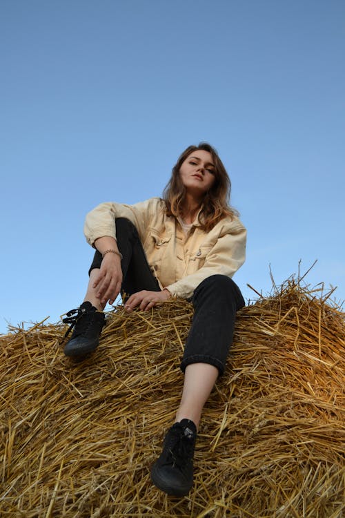 A Woman in Yellow Jacket Sitting on Hay Bale