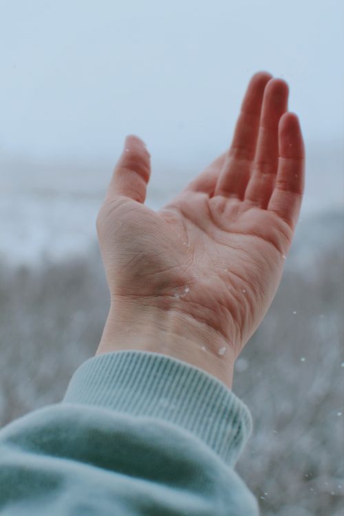 Free A close-up view of an open hand catching snowflakes, evoking a wintry and serene feel. Stock Photo