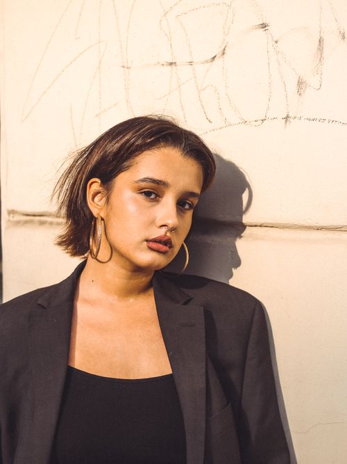 Free Fashionable woman in black blazer with hoop earrings against a graffiti wall. Stock Photo