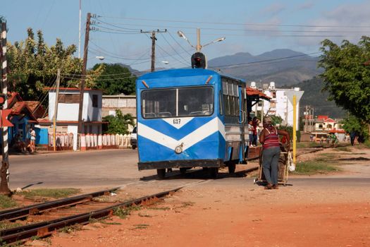 A classic blue train crossing a rural area with mountains in the background, capturing a serene countryside moment.