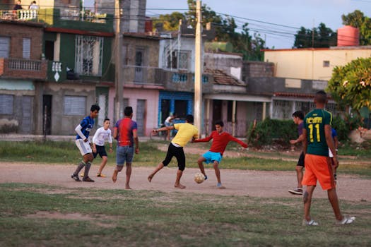 Group of young men playing soccer outdoors in a city neighborhood.