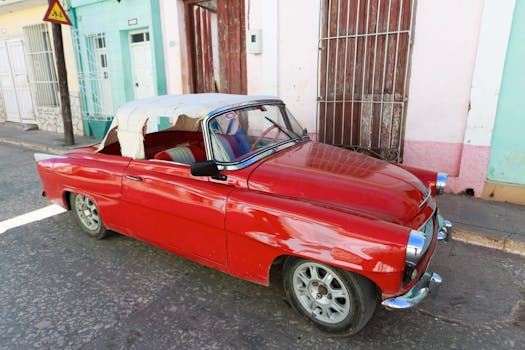 Classic red convertible car parked in a vibrant historical street, perfect for vintage enthusiasts.