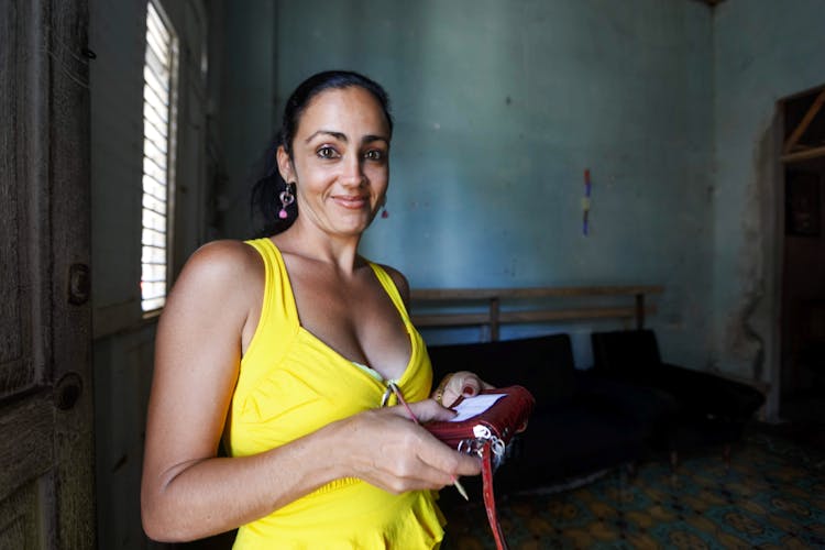 A Woman In A Yellow Sleeveless Top Holding Her Purse