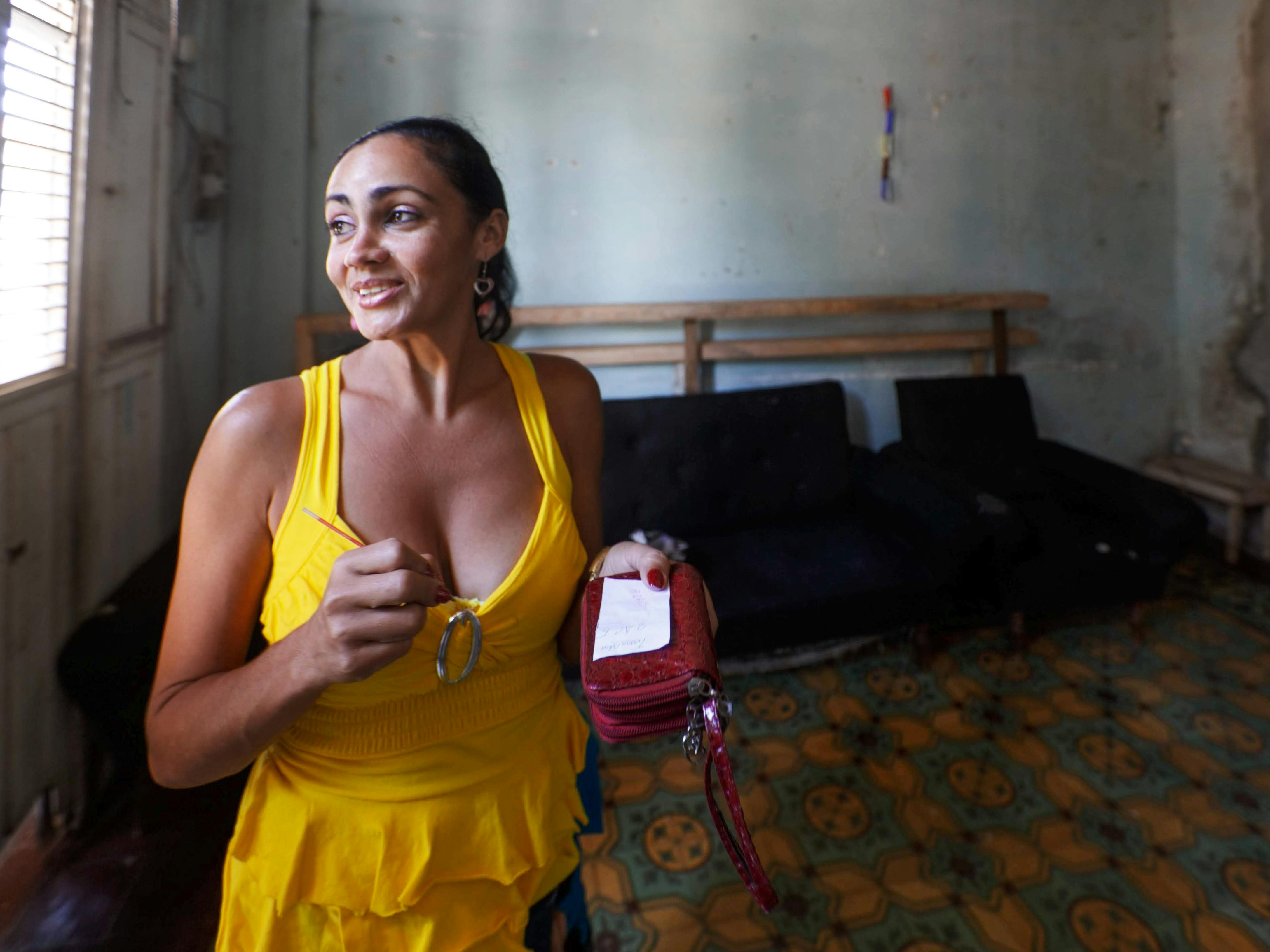 Free A fashionable woman smiles warmly while standing in a vibrant yellow dress indoors. Stock Photo