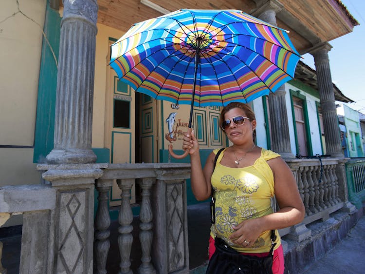 A Woman In A Yellow Top Using An Umbrella 